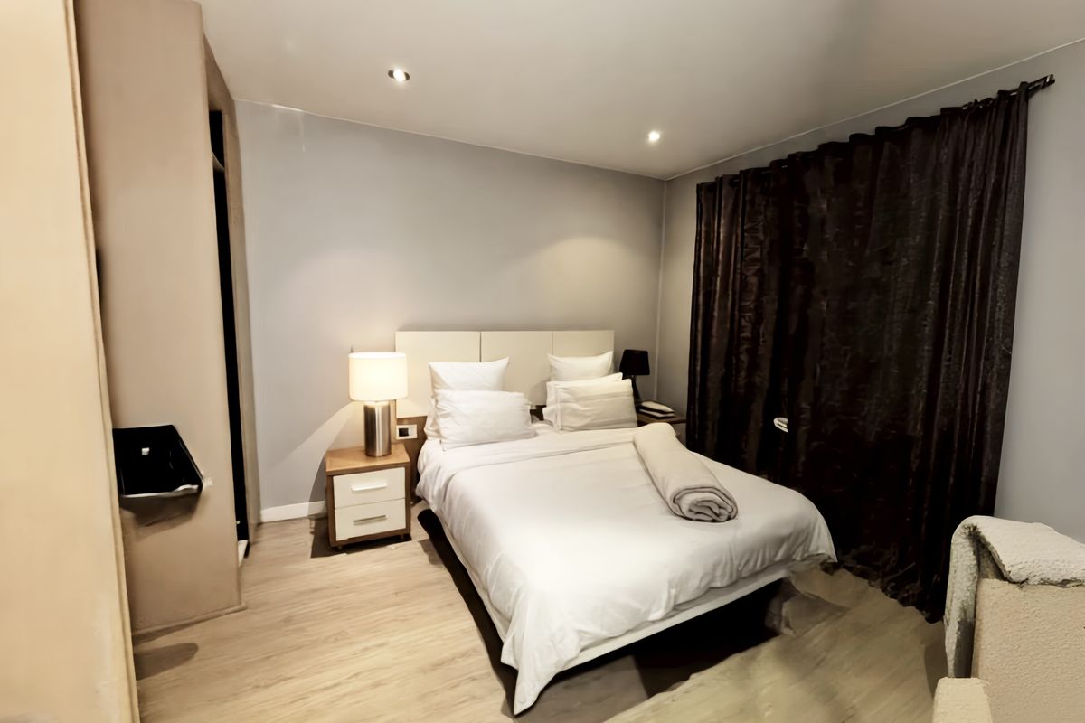 A well-maintained bedroom featuring laminate flooring, recessed downlighting, and a built-in wardrobe, offering a comfortable and functional living space.