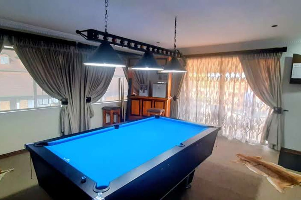 A dedicated entertainment room featuring a pool table, built-in bar area, and sliding door access to the exterior.