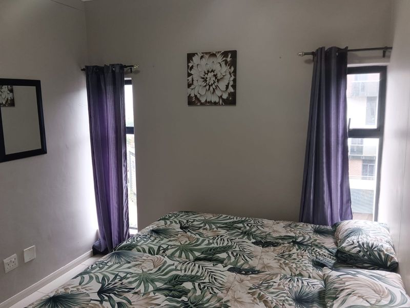 A bedroom featuring two windows with curtain rods and tiled flooring.