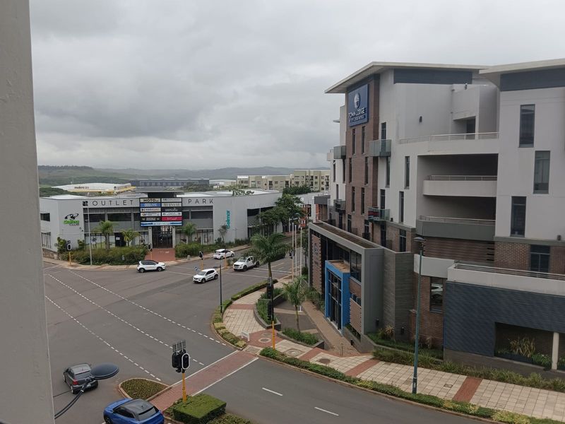 Elevated view overlooking the surrounding urban landscape, including nearby commercial buildings, street infrastructure, and modern apartment complex architecture.