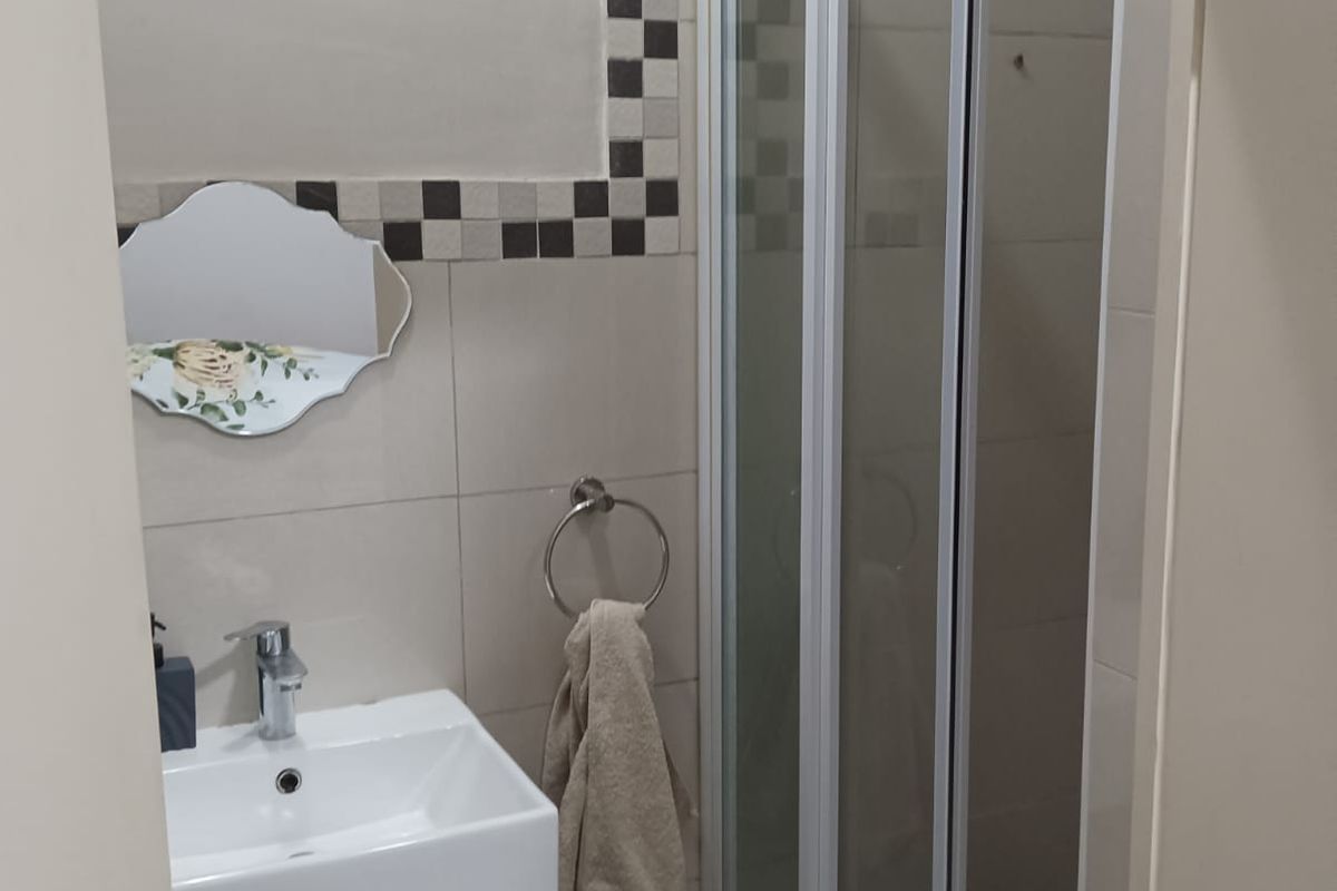 Compact bathroom featuring a modern vanity with basin, a glass-enclosed shower, and decorative mosaic tile accents.