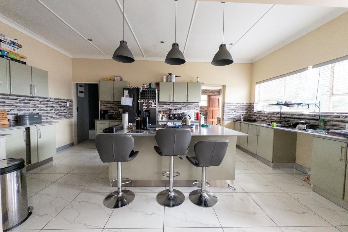 Spacious kitchen featuring a central island with breakfast bar, modern cabinetry, tiled flooring, and pendant lighting, offering a functional layout for daily use.