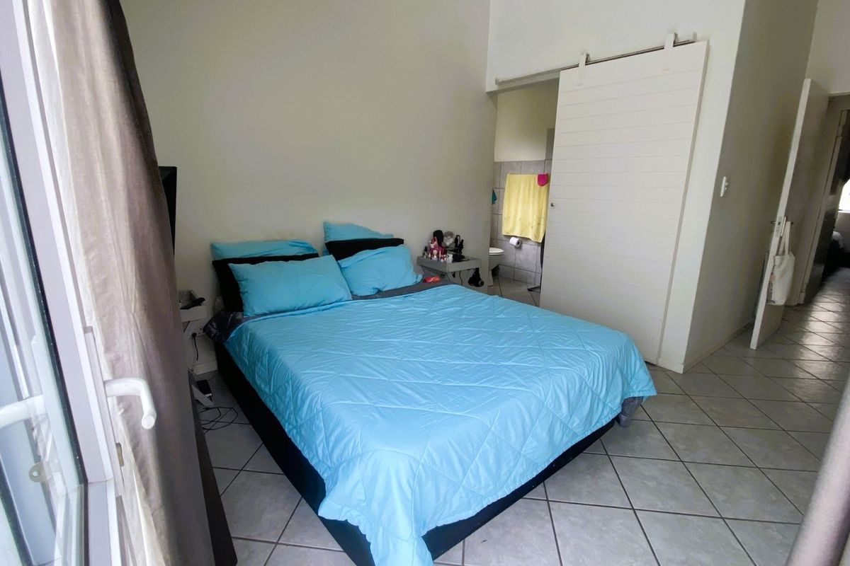 A bedroom featuring tiled flooring and a sliding barn-style door leading to an en-suite bathroom.