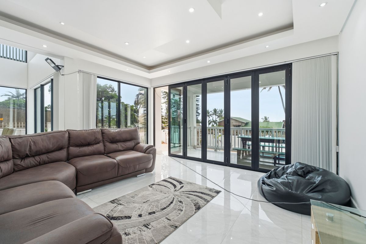 Spacious living area featuring large glass sliding doors that open onto a covered patio, providing seamless indoor-outdoor flow and abundant natural light.
