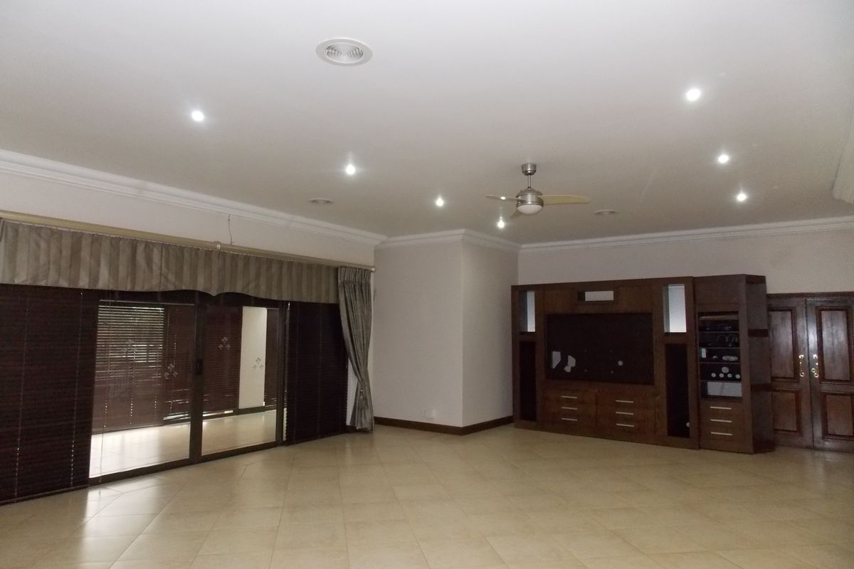 Spacious living room featuring large sliding glass doors, built-in wooden cabinetry, recessed downlighting, and a ceiling fan.