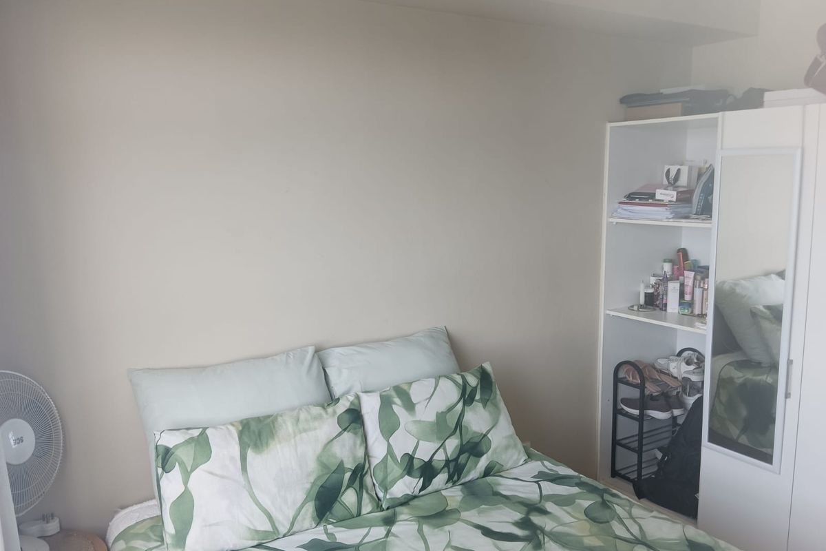 A functional bedroom space featuring neutral wall tones and a built-in storage unit with an integrated mirror.