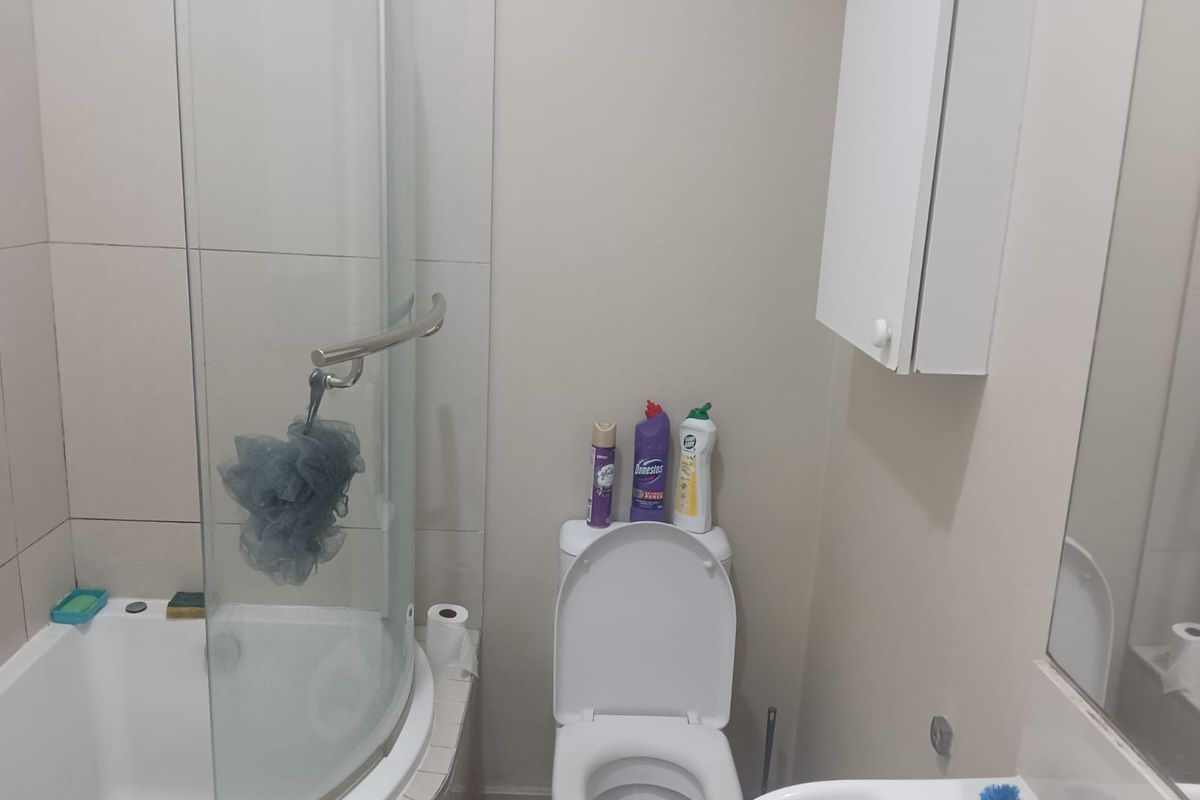 A functional bathroom featuring a corner shower enclosure, a standard toilet, and a wall-mounted medicine cabinet.