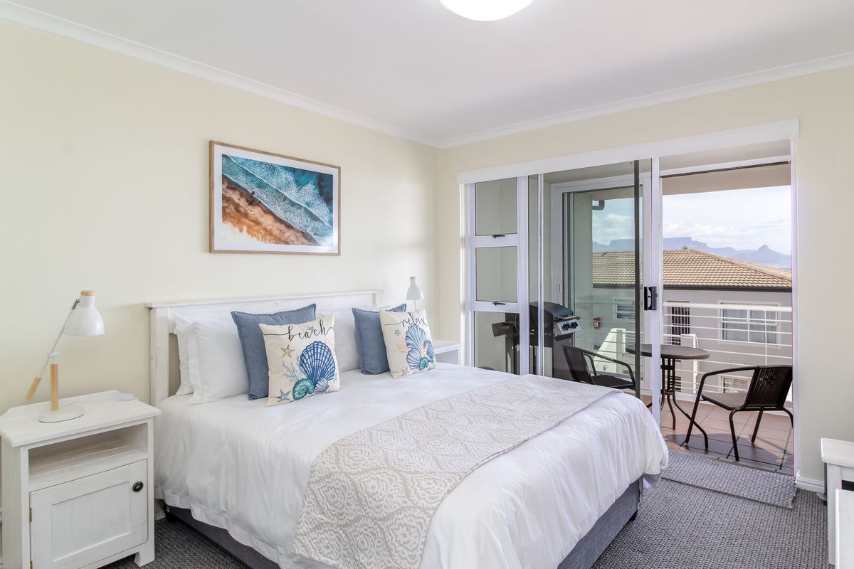 Bright bedroom featuring neutral finishes, carpeted flooring, and large sliding glass doors providing direct access to a private balcony with mountain views.