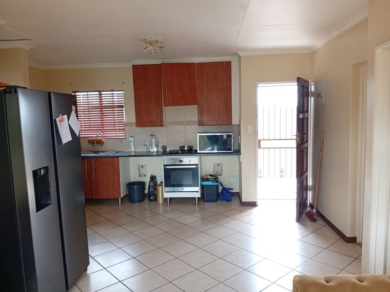 Kitchen area featuring tiled flooring, built-in cabinetry, and an integrated oven and hob, with direct access to an exterior door.