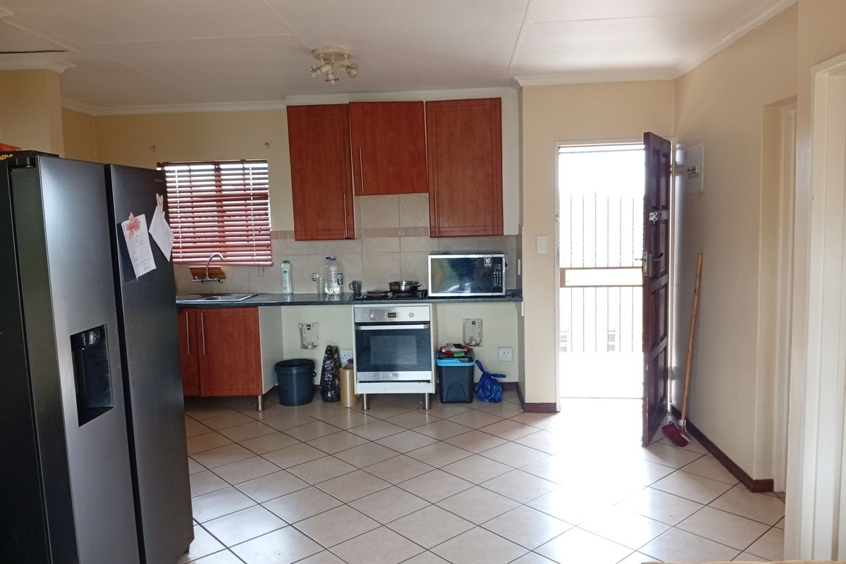 Kitchen area featuring tiled flooring, built-in cabinetry, and an integrated oven and hob, with direct access to an exterior door.