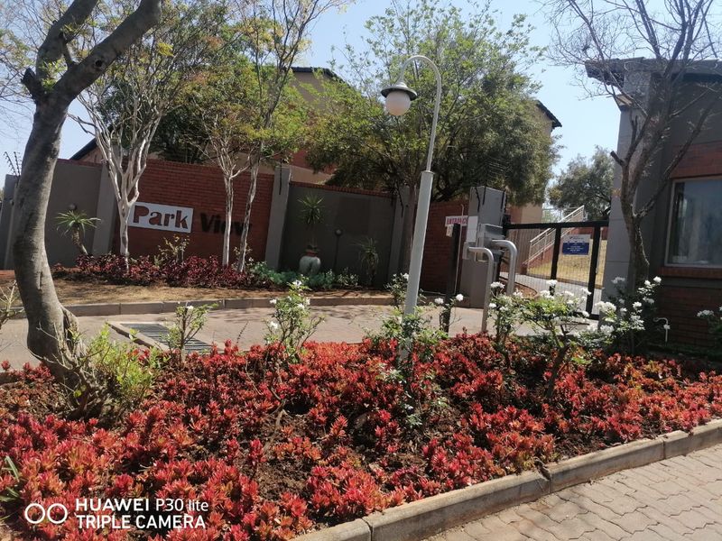 The entrance to Park View complex featuring a brick boundary wall, electric fencing, secure gate access, and well-maintained landscaped gardens.
