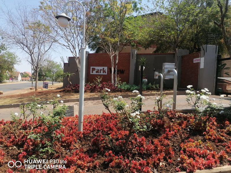 The entrance to Park View complex featuring a brick boundary wall, security gate, electric fencing, and established garden landscaping.