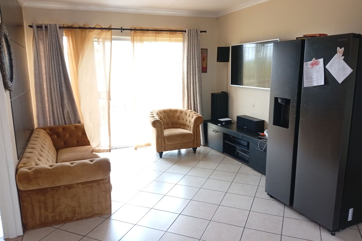 A living room featuring tiled flooring and a large sliding glass door providing natural light and access to the exterior.