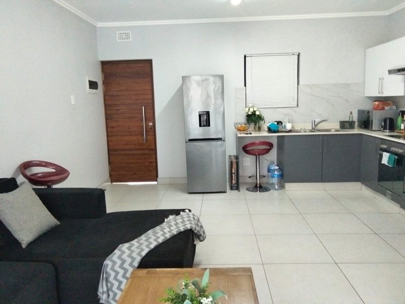 Open-plan living area featuring a modern kitchen with grey cabinetry, integrated oven, and tiled flooring throughout.