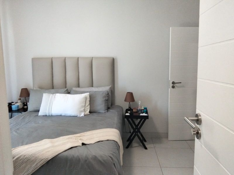 A well-maintained bedroom featuring neutral wall tones, modern tiled flooring, and a contemporary horizontal-panel interior door.