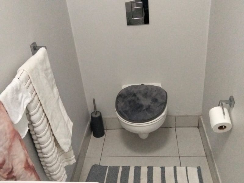 A compact bathroom featuring a wall-mounted toilet with a concealed cistern, tiled flooring, and a modern basin.
