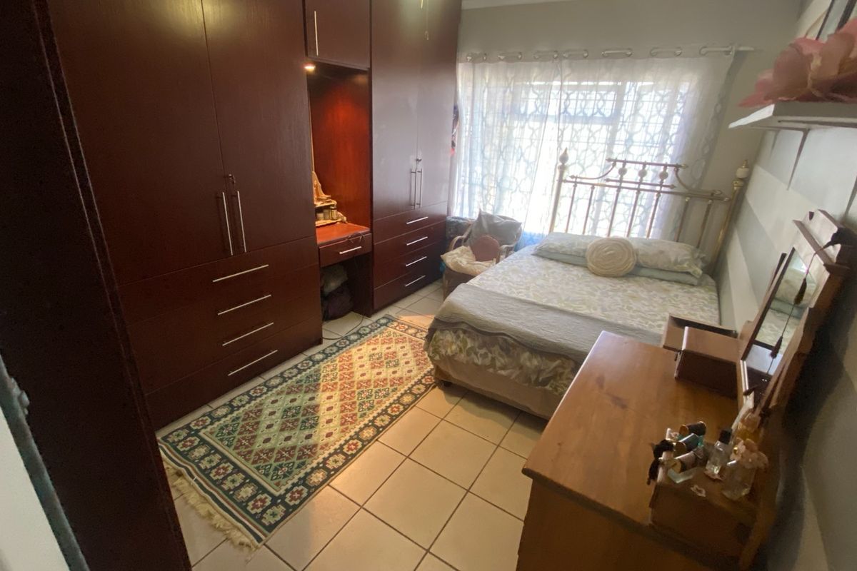 A bedroom featuring built-in dark wood cabinetry with an integrated vanity area and tiled flooring.