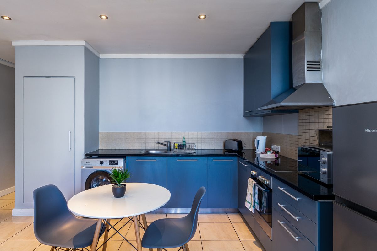 Modern kitchen featuring blue cabinetry, black granite countertops, integrated appliances, tiled backsplash, and recessed lighting, offering a functional and contemporary cooking space.