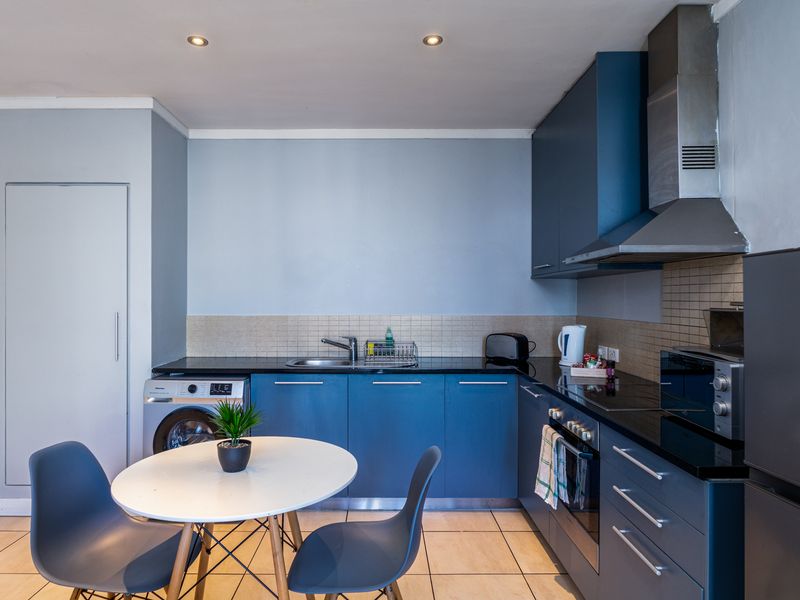 Modern kitchen featuring blue cabinetry, black granite countertops, integrated appliances, tiled backsplash, and recessed lighting, offering a functional and contemporary cooking space.