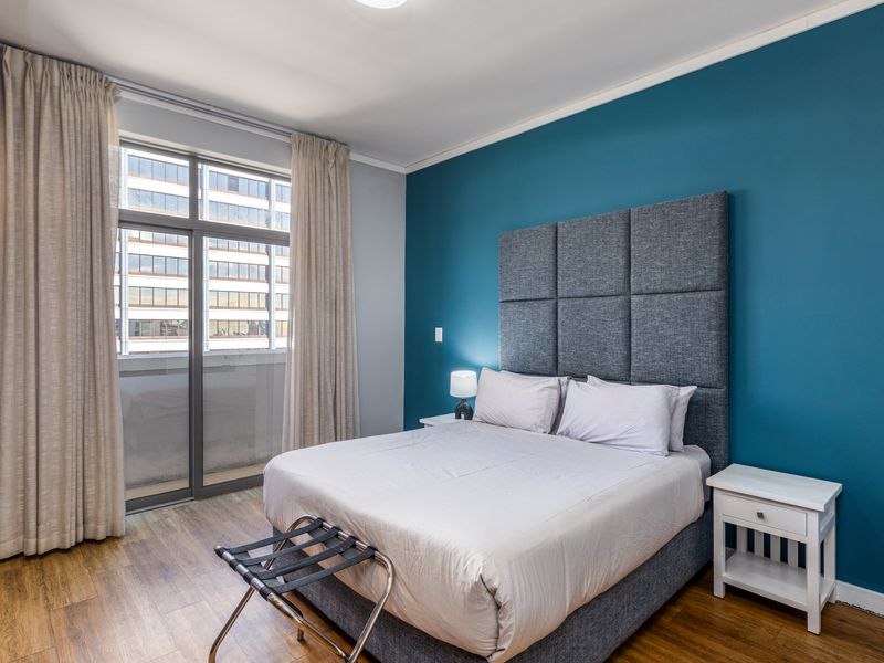 A well-maintained bedroom featuring laminate flooring, a built-in wardrobe, and a large sliding glass door providing natural light.
