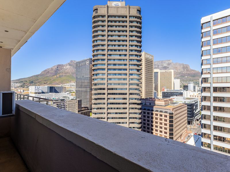 A balcony offering expansive urban views of the city skyline and mountain backdrop.