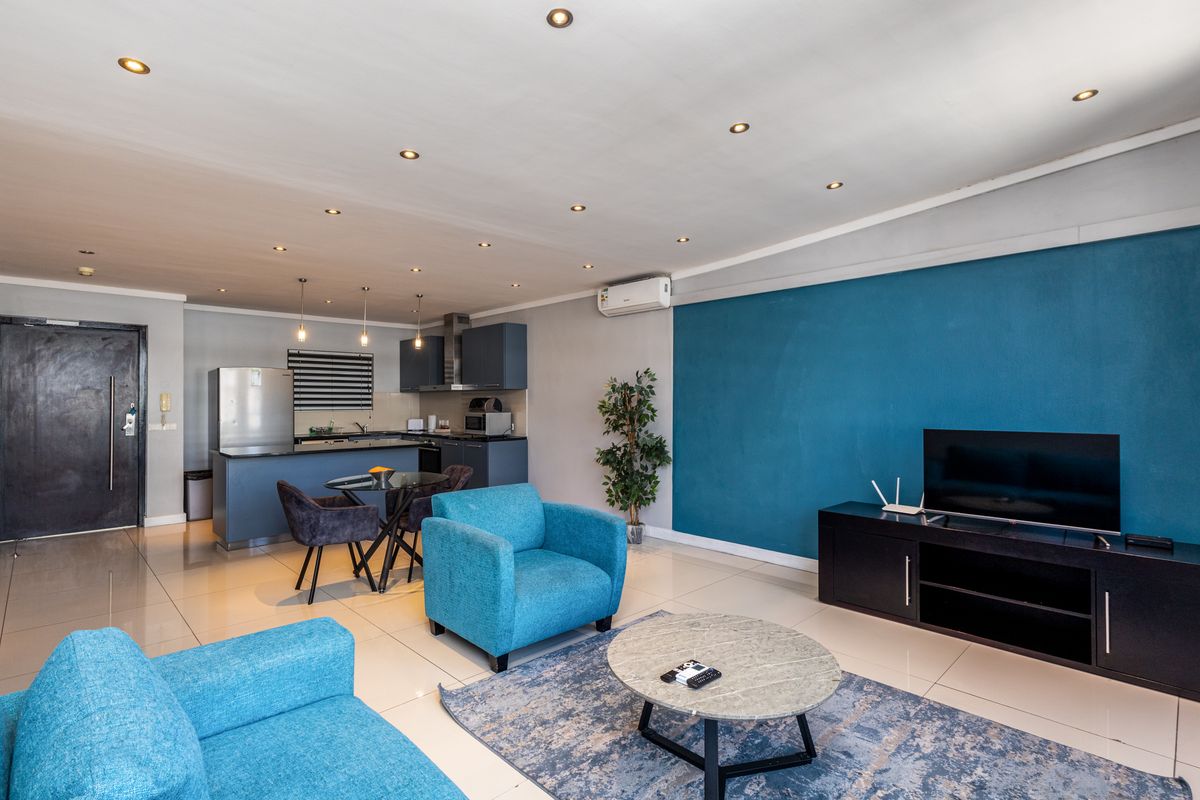 An open-plan living and kitchen area featuring tiled floors, recessed lighting, a split-system air conditioner, and a modern kitchen layout.