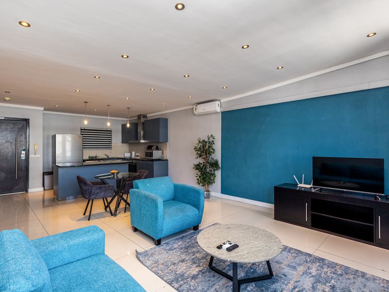 An open-plan living and kitchen area featuring tiled floors, recessed lighting, a split-system air conditioner, and a modern kitchen layout.