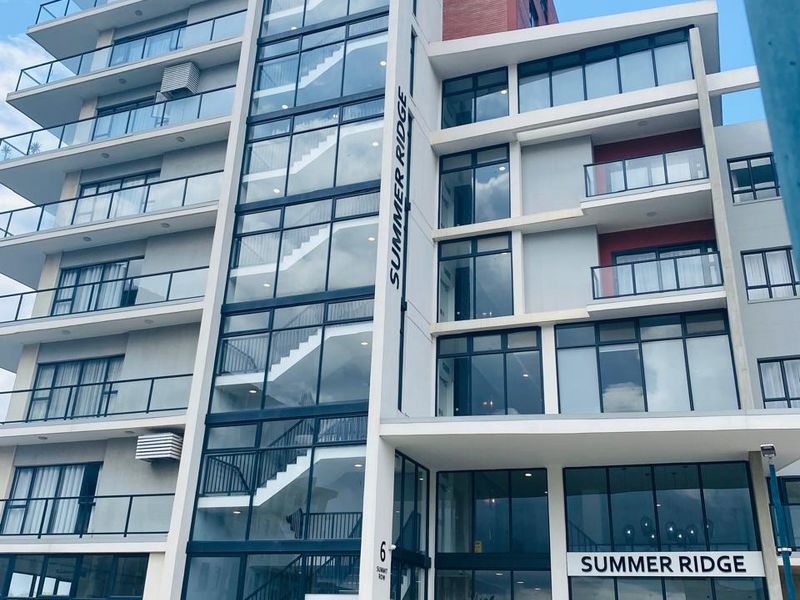 Modern multi-story apartment building facade featuring glass-enclosed stairwells, private balconies, and contemporary architectural design.