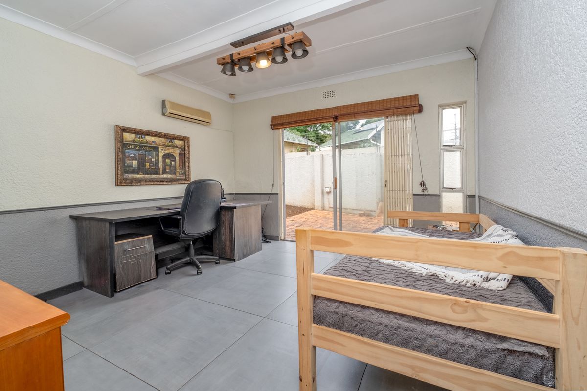 A bedroom featuring tiled flooring, an air conditioning unit, and sliding glass doors providing direct access to the rear patio area.