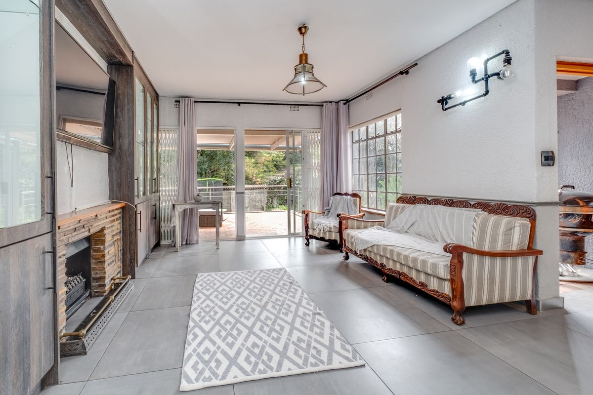 Spacious living room featuring large format floor tiles, a built-in fireplace with integrated cabinetry, and sliding doors leading to an outdoor patio area.