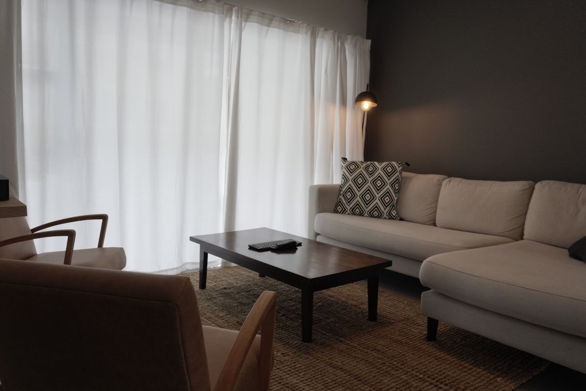 A cozy living room featuring a dark accent wall and large floor-to-ceiling curtains, creating a comfortable and inviting atmosphere.