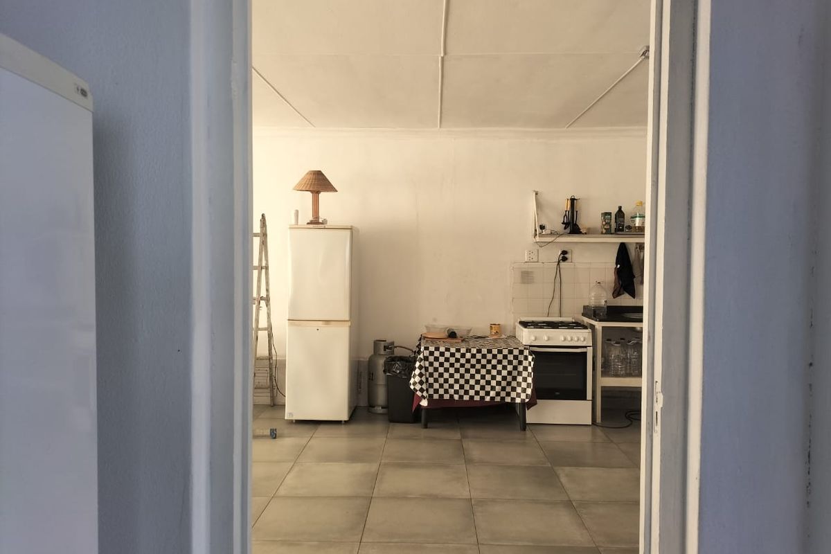 A functional kitchen space featuring tiled flooring, a freestanding stove, and basic shelving, viewed through a doorway.