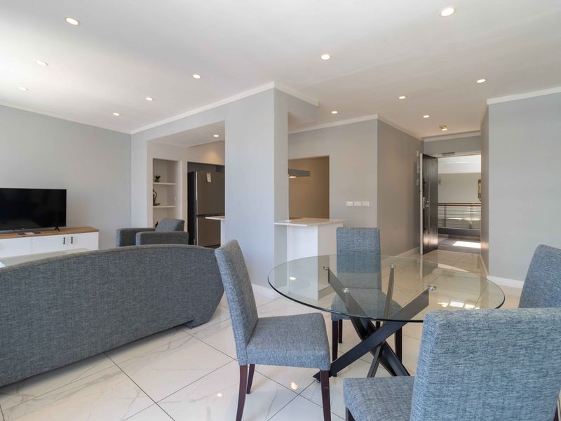 Modern open-plan living and dining area featuring polished porcelain floor tiles, recessed lighting, and a seamless transition to the kitchen space.