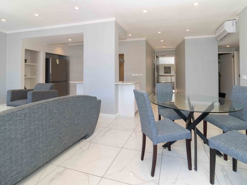 Bright open-plan living and dining area featuring modern marble-look floor tiles, recessed lighting, and a split-system air conditioner.