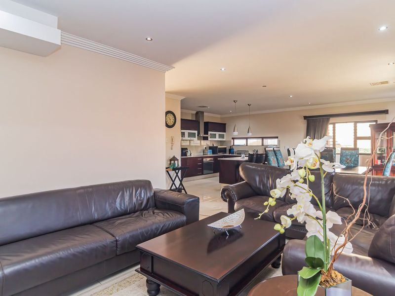 Spacious open-plan living area featuring a modern kitchen with dark cabinetry, integrated appliances, and recessed downlighting throughout the connected dining and lounge spaces.
