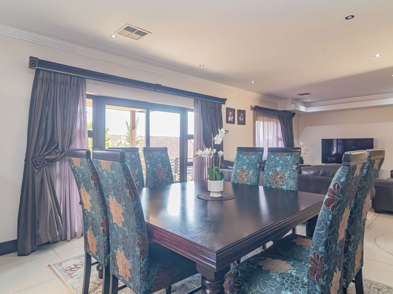 Open plan dining and living area featuring tiled flooring, recessed downlighting, and large sliding glass doors providing access to the outdoor patio.