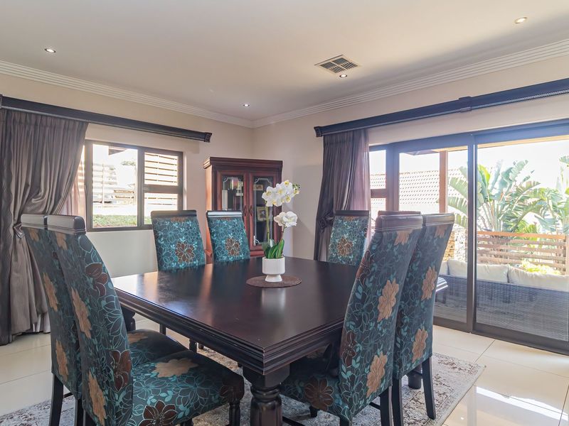 A well-lit dining room featuring tiled flooring, recessed ceiling lighting, and large sliding glass doors providing direct access to an outdoor patio area.