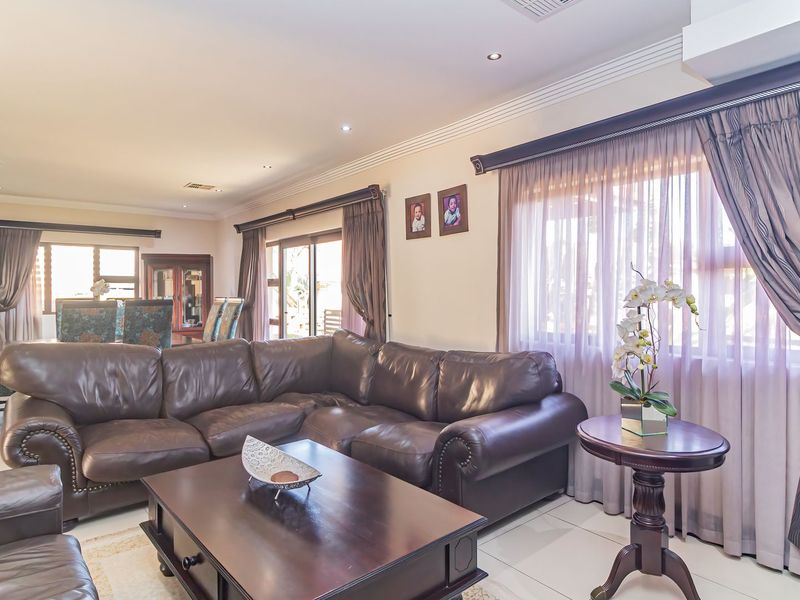 Spacious living room featuring tiled flooring, recessed downlighting, and large windows with integrated curtain tracks, offering a bright and comfortable living environment.
