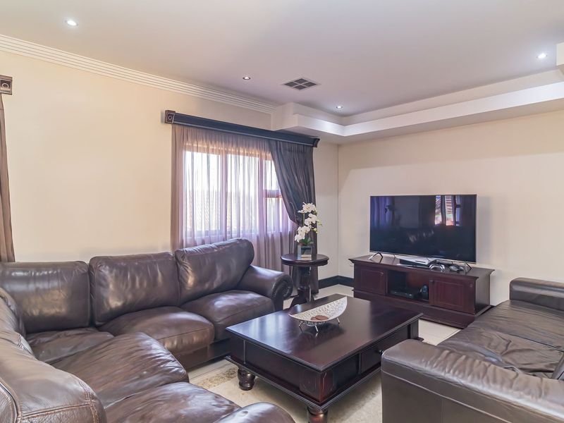 A comfortable living room featuring recessed ceiling lighting, a tray ceiling design, and large windows with fitted curtain tracks.