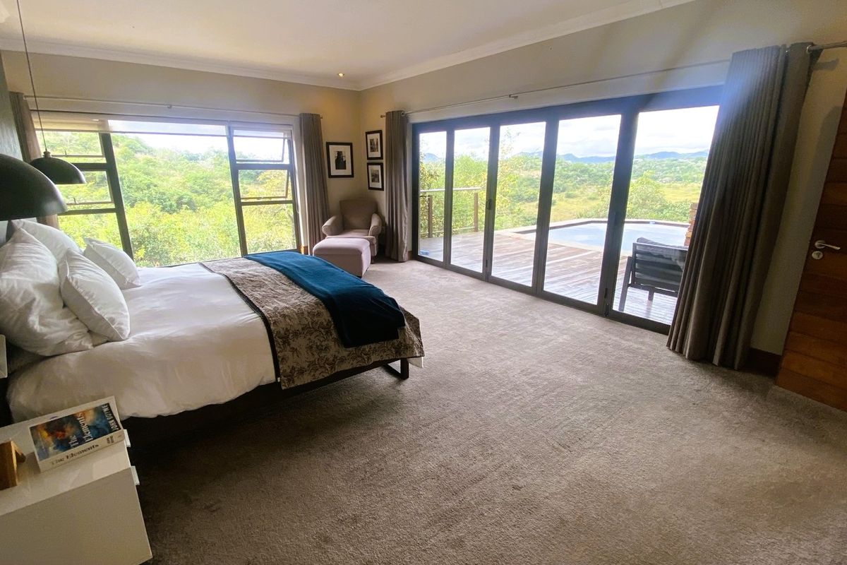 Spacious bedroom featuring large sliding glass doors that open onto a private deck with pool and scenic landscape views.