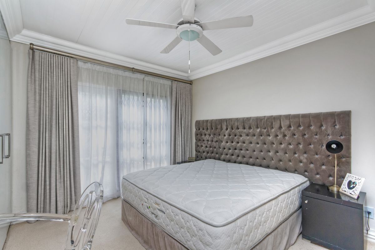 A well-maintained bedroom featuring crown molding, a ceiling fan, and sliding glass doors that provide access to the exterior.