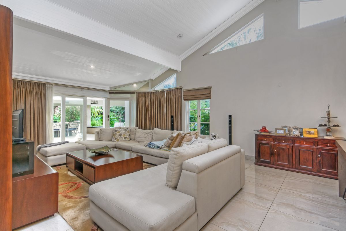 Spacious living room featuring high vaulted ceilings, large sliding glass doors leading to the patio, and bright natural light from clerestory windows.