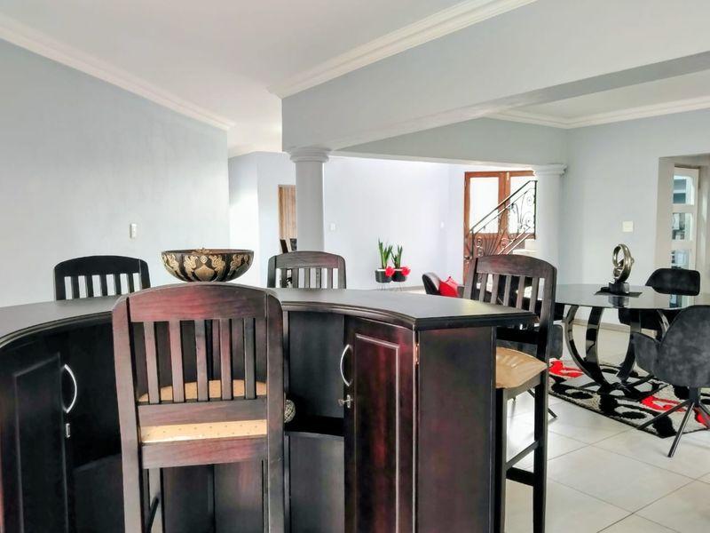 Open plan living area featuring tiled flooring, decorative crown molding, and a central structural column connecting to the dining space.