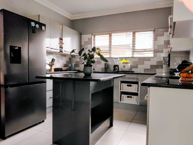 Modern kitchen featuring a central island, sleek cabinetry, granite countertops, and a stylish subway tile backsplash with integrated lighting.