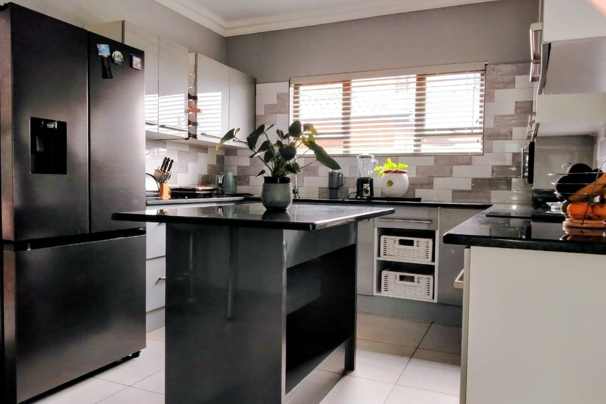 Modern kitchen featuring a central island, sleek cabinetry, granite countertops, and a stylish subway tile backsplash with integrated lighting.