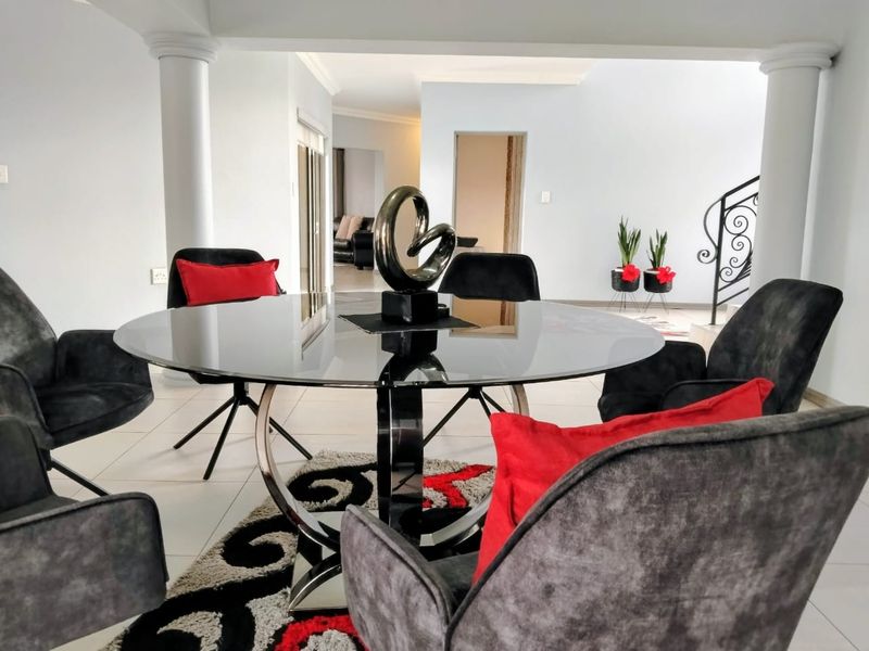 A bright and open dining area featuring tiled flooring, decorative columns, and a clear view into the adjacent living space.