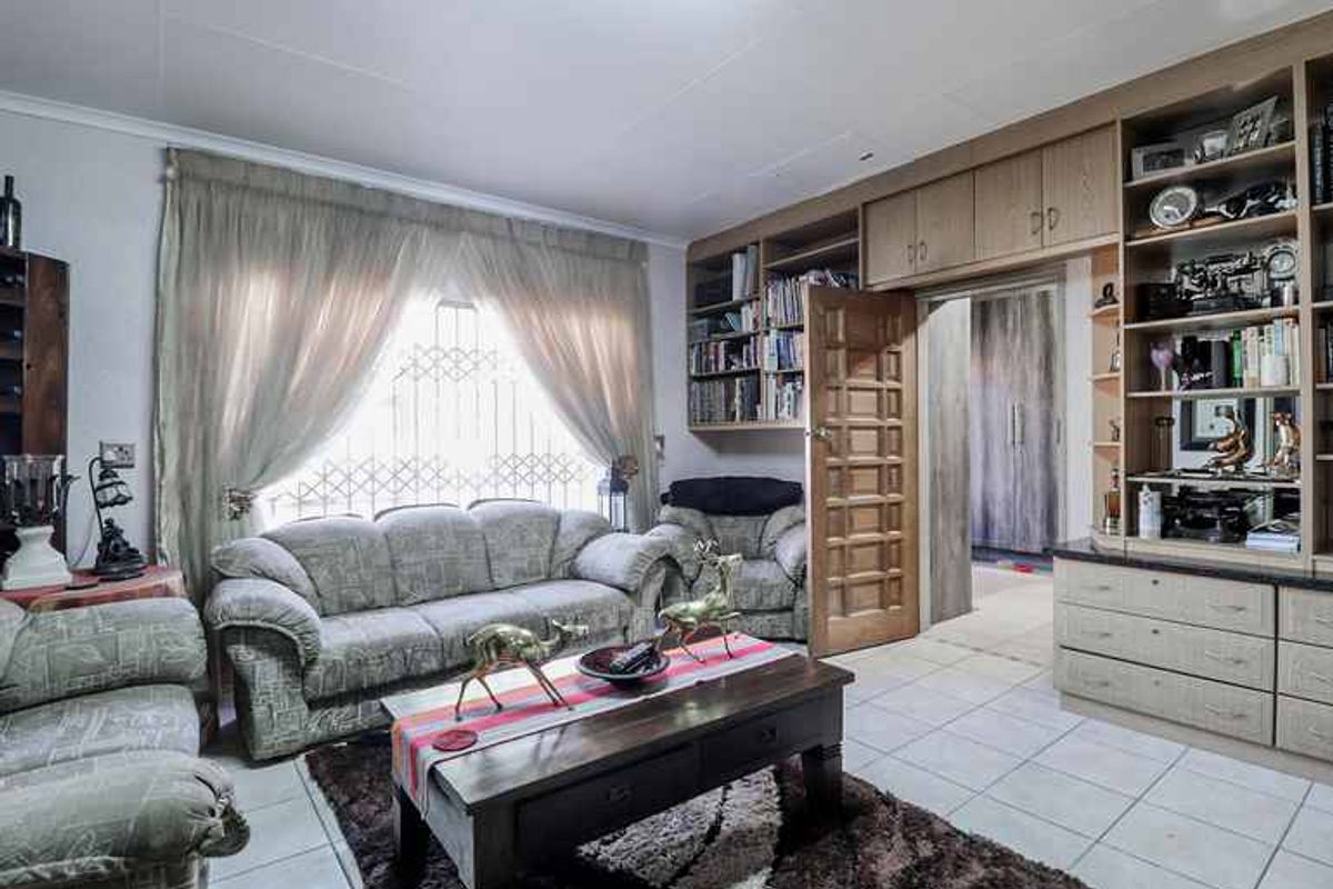 A living room featuring built-in wooden cabinetry, shelving units, and tiled flooring, with a doorway leading to an adjacent room.