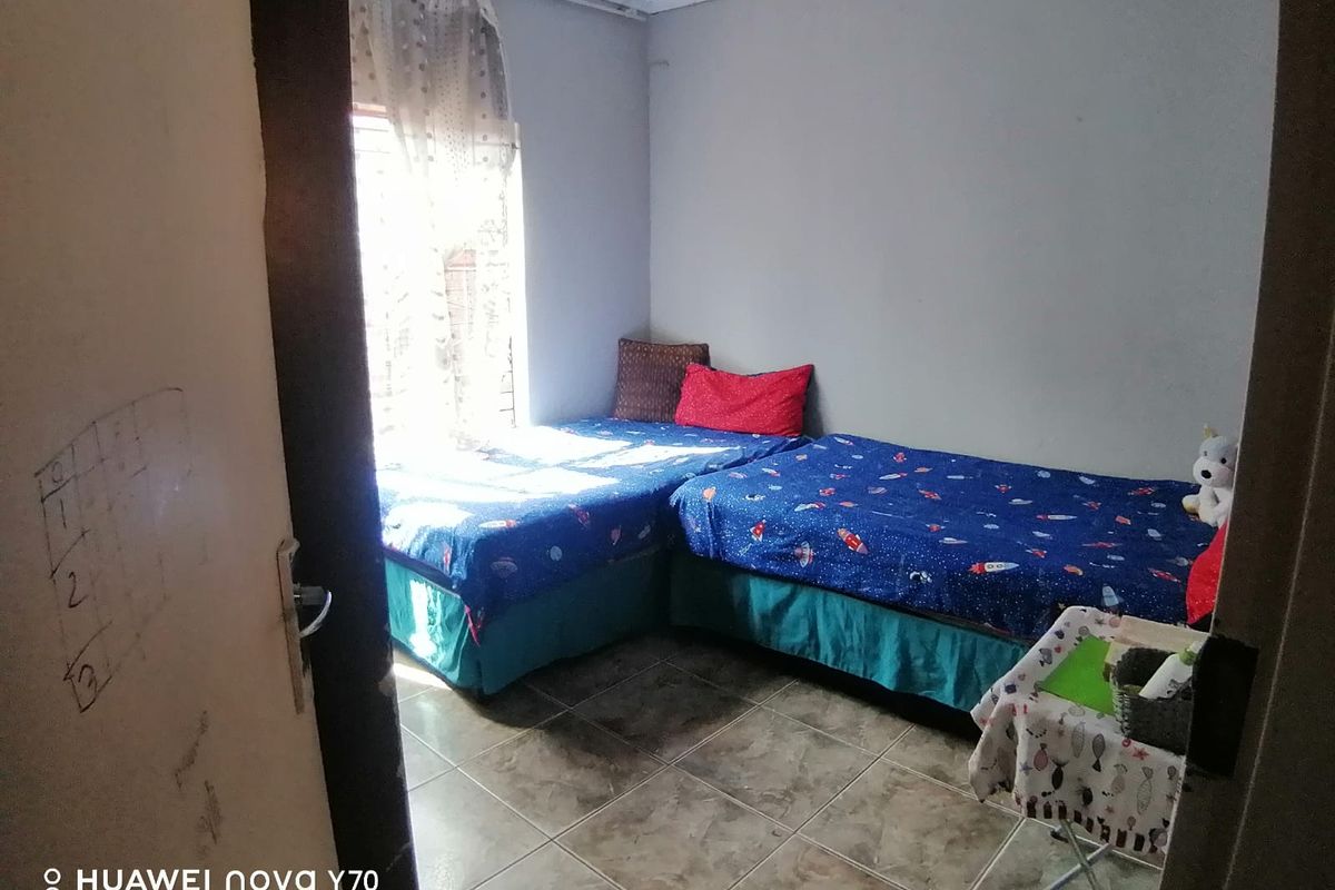 A functional bedroom featuring tiled flooring and natural light, providing a simple and practical living space.