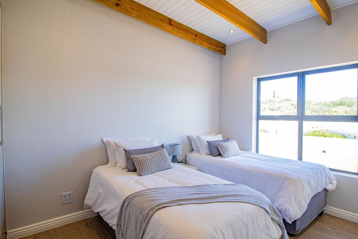 A bright bedroom featuring exposed timber ceiling beams, built-in cabinetry, and large windows providing natural light.
