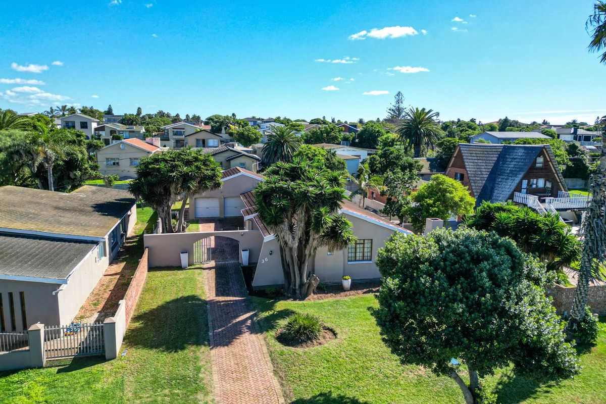 Aerial view of the property showcasing the front garden, paved driveway, double garage, and surrounding residential neighborhood.
